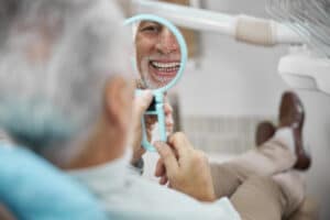 aged patient sitting dental chair while looking himself mirror Blog