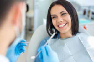 smiling woman dental chair with doctor holding dental mirror 1 Blog
