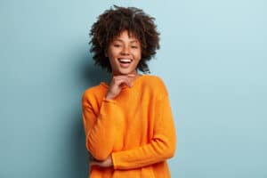 young woman with afro haircut wearing orange jumper Blog